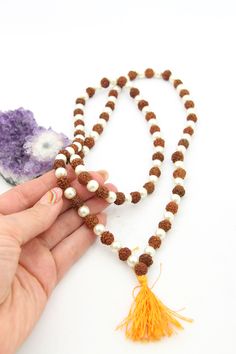 These beautiful beads are made from Rudraksha seeds paired with pearls. Hailing from India, Rudraksha seeds are traditionally used as prayer beads in Hinduism. They are the seeds of the Rudraksha tree, and legend has it that when Lord Shiva awoke from a long meditation, he shed a tear; from this tear grew the Rudraksha tree.Pearls are known as "moti" in Hindi, and they are symbolic of the moon. They encourage positive thinking and balance, and are believed to attract good luck and wealth. Bead S Spiritual White Necklace For Rituals, Spiritual White Necklaces For Rituals, 8mm Pearl Beads Spiritual Necklace, Traditional White Necklace For Healing, Spiritual Beaded Mala For Diwali, White Pearl Spiritual Beaded Necklace, Temple Jewelry Pearl Necklace With Round Beads, Pearl Necklace With Gemstone Beads For Festivals And Gifts, Spiritual White Jewelry For Rituals