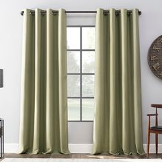 a living room with a large window covered in green curtains and a clock on the wall