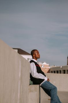 a man sitting on top of a cement wall