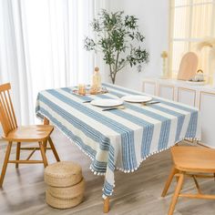 a dining table with blue and white striped cloth on it, next to two wooden chairs