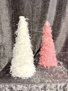 two small white and pink trees sitting on top of a gray couch next to each other