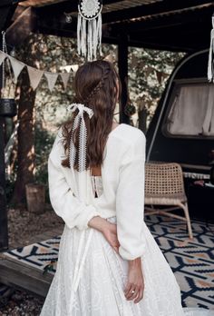 a woman in a white dress is sitting on the ground with her back to the camera