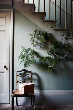 a chair sitting in front of a staircase with wreaths hanging on it