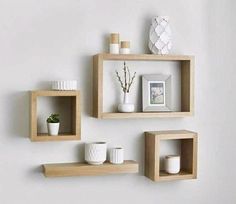 three wooden shelves on the wall with vases and other items sitting on top of them