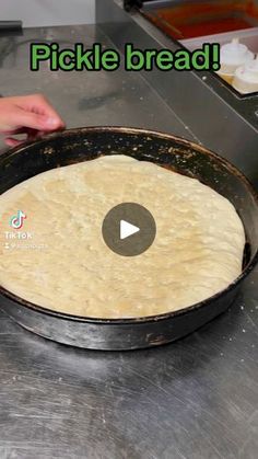 a person is making pizza dough in a pan on the counter with words that read pickle bread