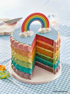 a rainbow cake on a plate with a slice cut out