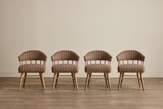 three chairs sitting side by side in front of a white wall and wood flooring