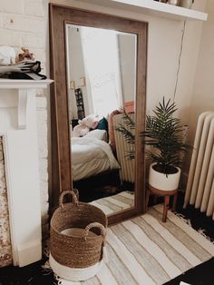 a mirror sitting on top of a wooden floor next to a rug and potted plant