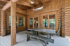 the inside of a log cabin with picnic table and benches