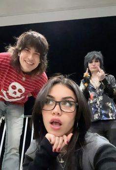 three people posing for the camera with one woman holding her hand up to her face