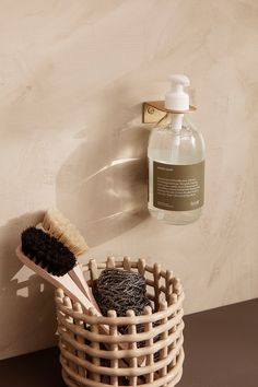 a wooden basket next to a wall with a brush and soap in it on the counter