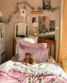 two teddy bears sitting on top of a bed in a room with pictures and plants