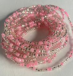 Elastic Waist Bead "Diawala" features strands of clear and silvery glass seed beads, elegantly adorned with delicate baby pink seed bead accents. Elevate your style with the timeless beauty of this harmonious blend, offering a touch of sophistication and gentle femininity. 💫 Clear and Silvery Radiance: This elastic waist bead gleams with clarity, adorned with clear and silvery glass seed beads that reflect a subtle, luminous radiance. The combination creates a versatile backdrop, allowing the a Adjustable Pink Beaded Bracelet With Silver Beads, Pink Tiny Beaded Bracelets For Party, Traditional Pink Adjustable Beaded Necklaces, Pink Beaded Necklaces For Festivals, Traditional Adjustable Pink Beaded Necklace, Gift Waist Beads With Tiny Beads, Gift Waist Beads With Small Beads, Gift Tiny Beads Waist Beads, Traditional Pink Beaded Necklaces