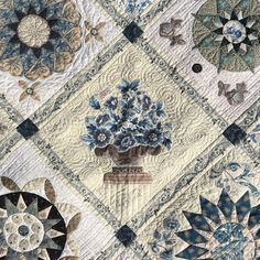 a quilted wall hanging with blue and white flowers in vases on the front