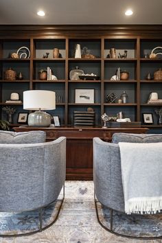 two gray chairs sitting in front of a book shelf