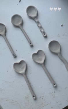 six spoons are arranged in the shape of hearts on a white surface with heart - shaped holes