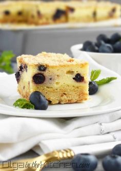 a slice of blueberry coffee cake on a plate with fresh berries and mint leaves