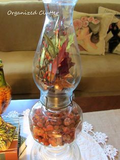 a glass vase filled with plants and nuts on top of a table next to a book