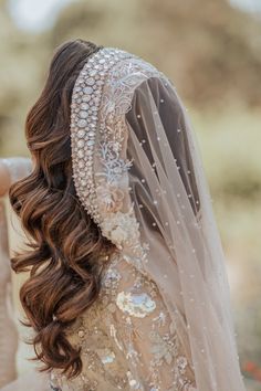 the back of a woman's head wearing a veil and hair comb with pearls on it