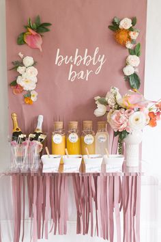 a table topped with bottles of champagne and flowers next to a sign that says bubbly bar