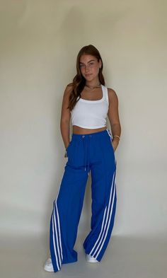 Step out with this edgy look for gamedays this fall! These blue track pants with side slits are the ultimate cool girl pant for Caturdays. So cute with chunky sneakers, or even heels for an elevated look. White stripes down the side & drawstring waist. Model is 5'5" with a 34 bust, 26" waist, 32" hips, and wearing a small. Model typically wears a 4. This item runs true to size. Pants With Side Slits, Gameday Fits, Blue Track Pants, College Gameday Outfits, Gameday Outfits, College Gameday, Cute Pants, Gameday Outfit, Chunky Sneakers