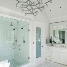 a large bathroom with a walk in shower next to a double sink and two sinks