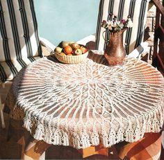 a crocheted tablecloth sits on an outdoor chair next to a bowl of fruit