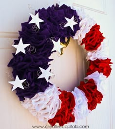 a wreath with red, white and blue ruffles is hanging on the door