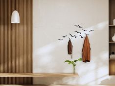 birds flying in the air above a wooden shelf with coat hooks on it and a potted plant