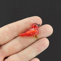 a small red bird sitting on top of a person's hand in front of a black background