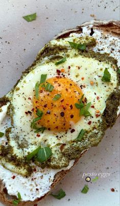 an egg is sitting on top of a piece of bread with pesto sprinkles