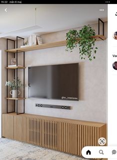 a flat screen tv mounted to the side of a wall next to a wooden shelf