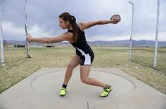 a woman is throwing a frisbee on a concrete surface in an open field