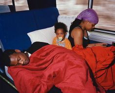 a man and woman laying in bed next to a child with a pacifier on their face