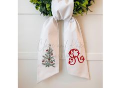 a white scarf with a christmas tree and monogrammed letters hanging on a door