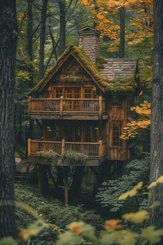 a tree house in the woods surrounded by trees and foliage with yellow leaves around it