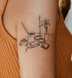 a woman's arm with a tattoo on it that has an image of a teapot, books and candles