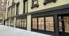 an empty sidewalk in front of a building with many windows on the side of it