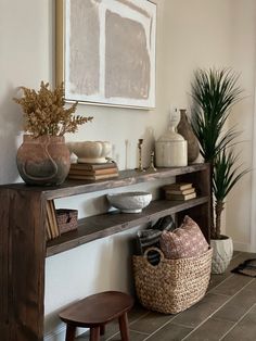 a wooden shelf sitting next to a potted plant on top of a table in a living room