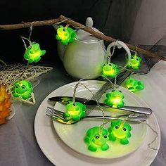 some little green frogs are sitting on a plate with forks and spoons in front of them