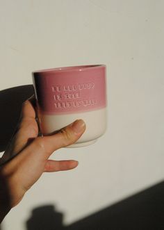 a hand holding a pink and white coffee cup with writing on it that says, we all need to love this stuff