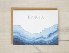 a card with the words thank you written on it in front of a wooden background