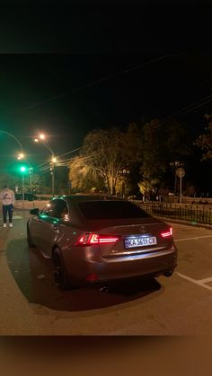 a car parked in the middle of a parking lot at night with two people walking by