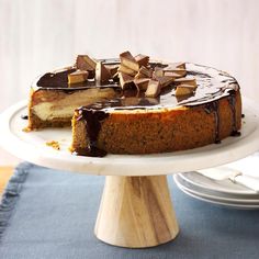 a cheesecake with chocolate toppings on a white cake platter, ready to be eaten