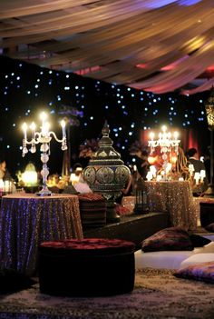 a room filled with lots of tables covered in purple and gold cloths, lit by candles