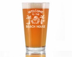 a beer glass with the words welcome to the beach house in white lettering on it