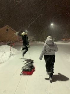 two people walking in the snow with sleds on their feet and one person jumping up into the air