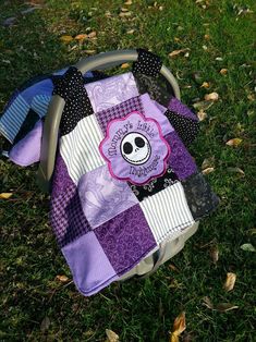 a purple and black patchwork bag with a skull on it sitting in the grass