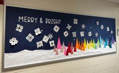 a bulletin board decorated with paper snowflakes and christmas trees on the wall in a school hallway