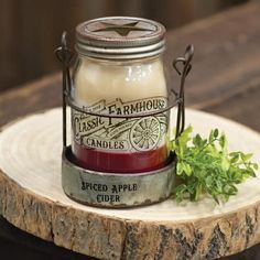 a small jar filled with candles sitting on top of a wooden table next to a plant